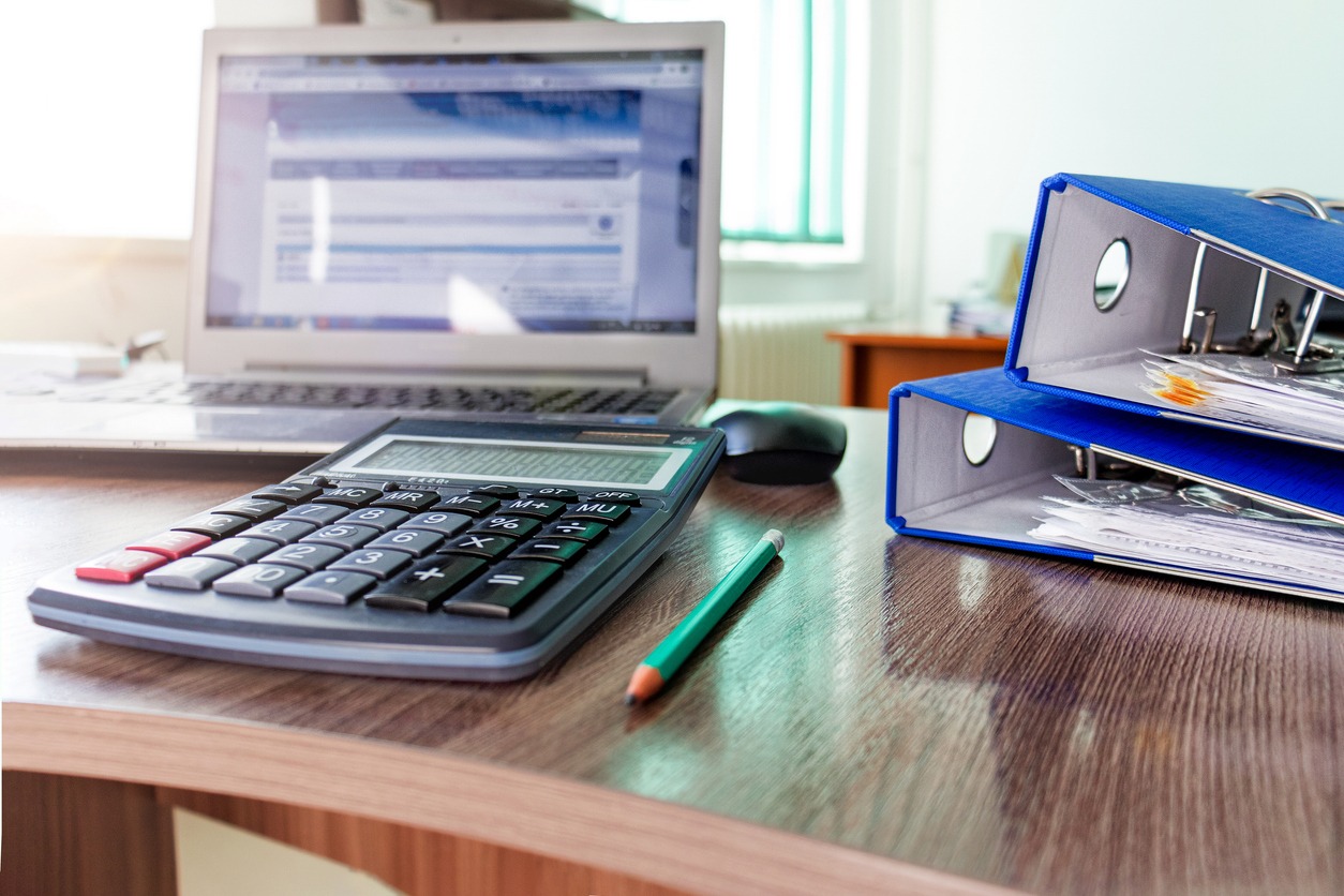 a desk with a calculator and a laptop