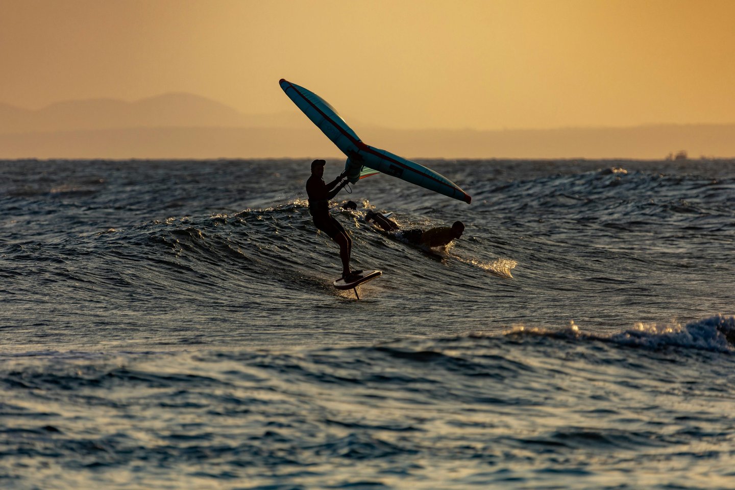 Wingfoil surfing on a wave during sunset