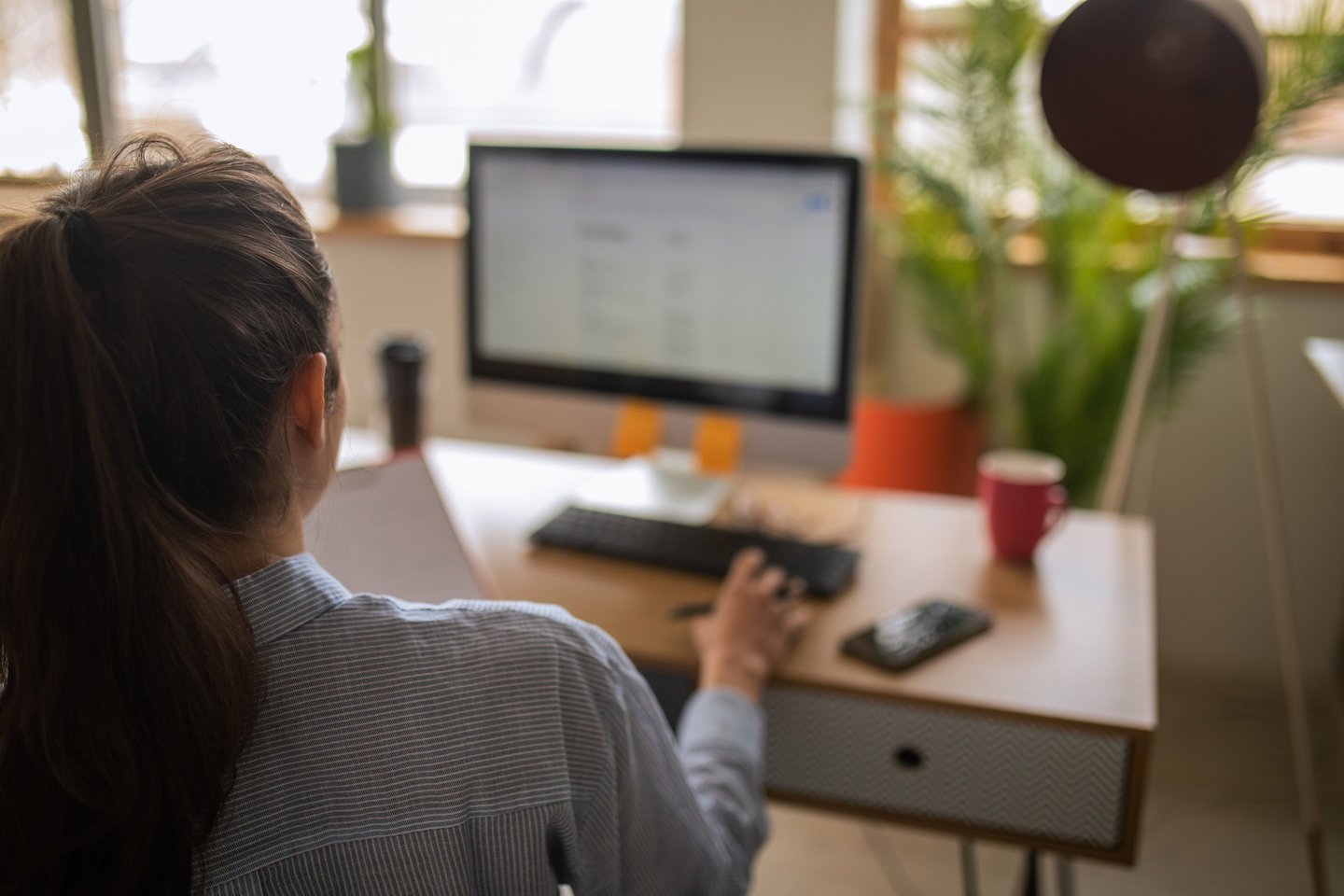 a woman sitting at a desk with a computer and a ball