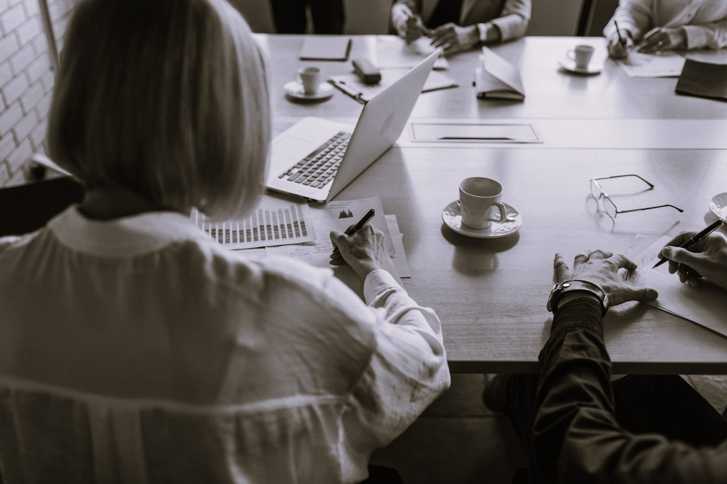 Femme assise à une table avec plusieurs personnes qui présente un projet commercial