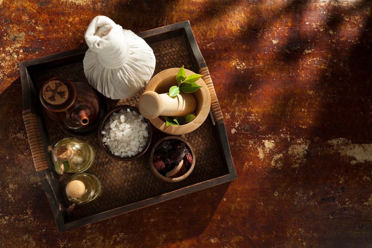 Plateau contenat des bols avec des plantes et du sel et des fioles avec des huiles