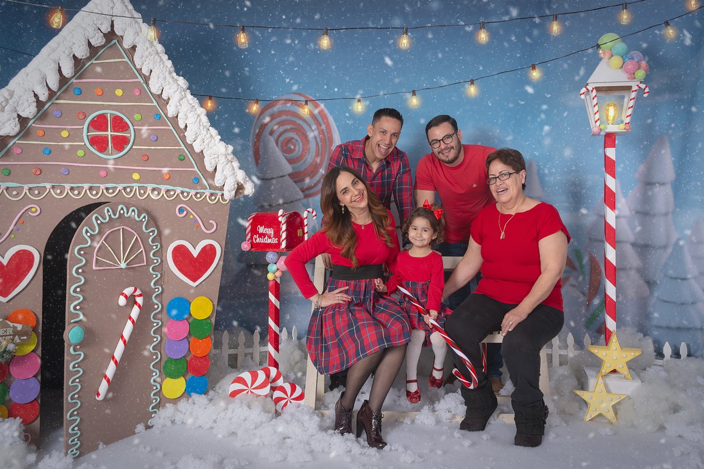 a family posing for a photo in front of a gingerbread house