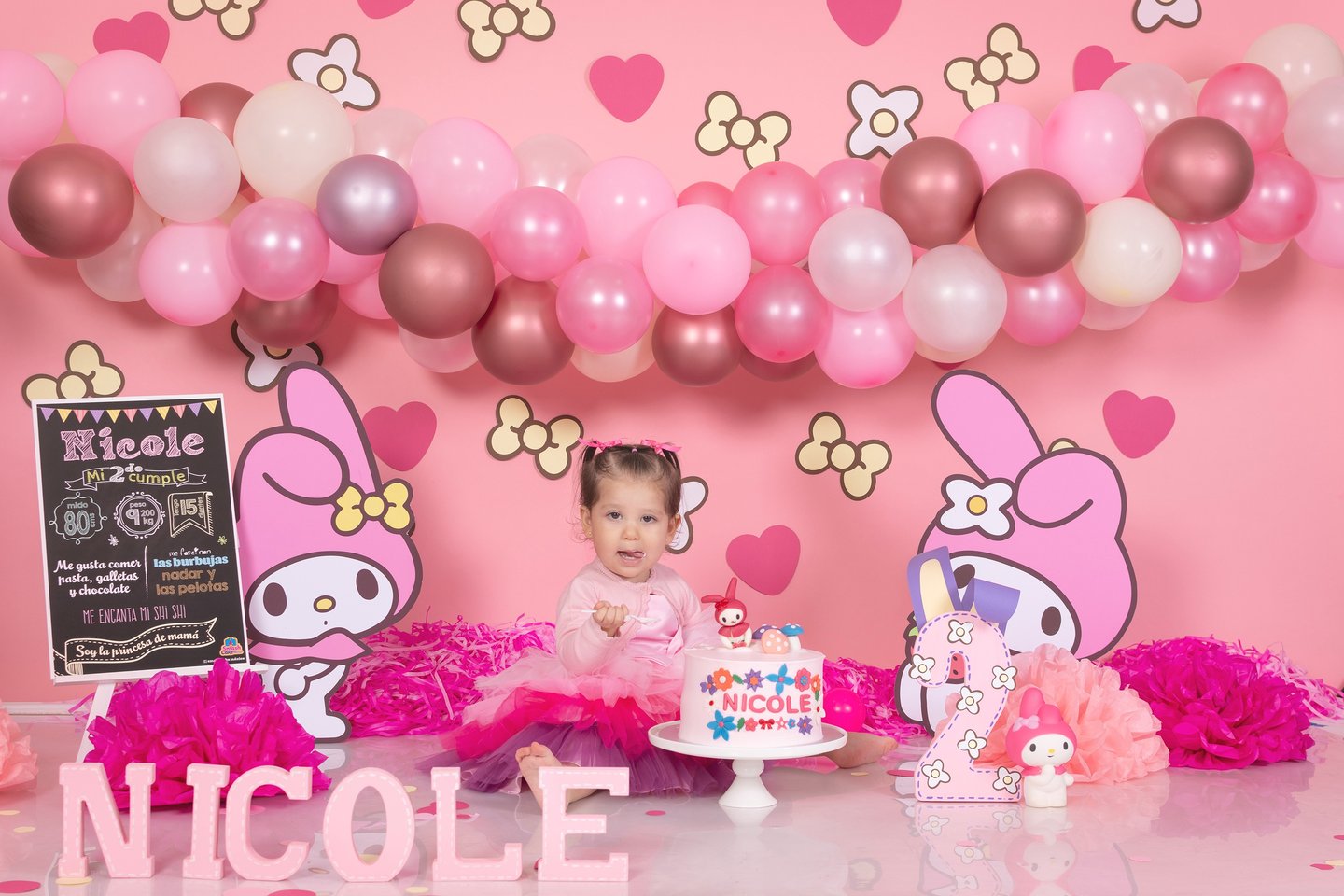 a baby girl in a pink dress and pink balloons