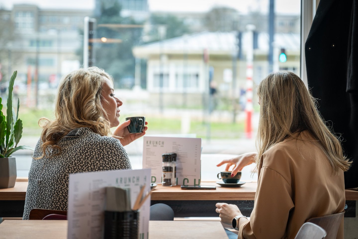 Twee bezoekers genieten van een koffie aan het raam bij Krunch Gent