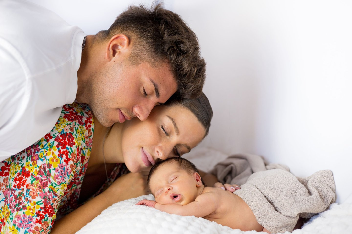 Sessió de fotos newborn a Girona amb bebè recent nascuda dormint amb els pares en estudi fotogràfic