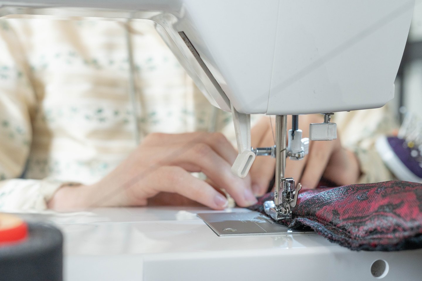 Gros plan sur des mains guidant le tissus sur une machine à coudre