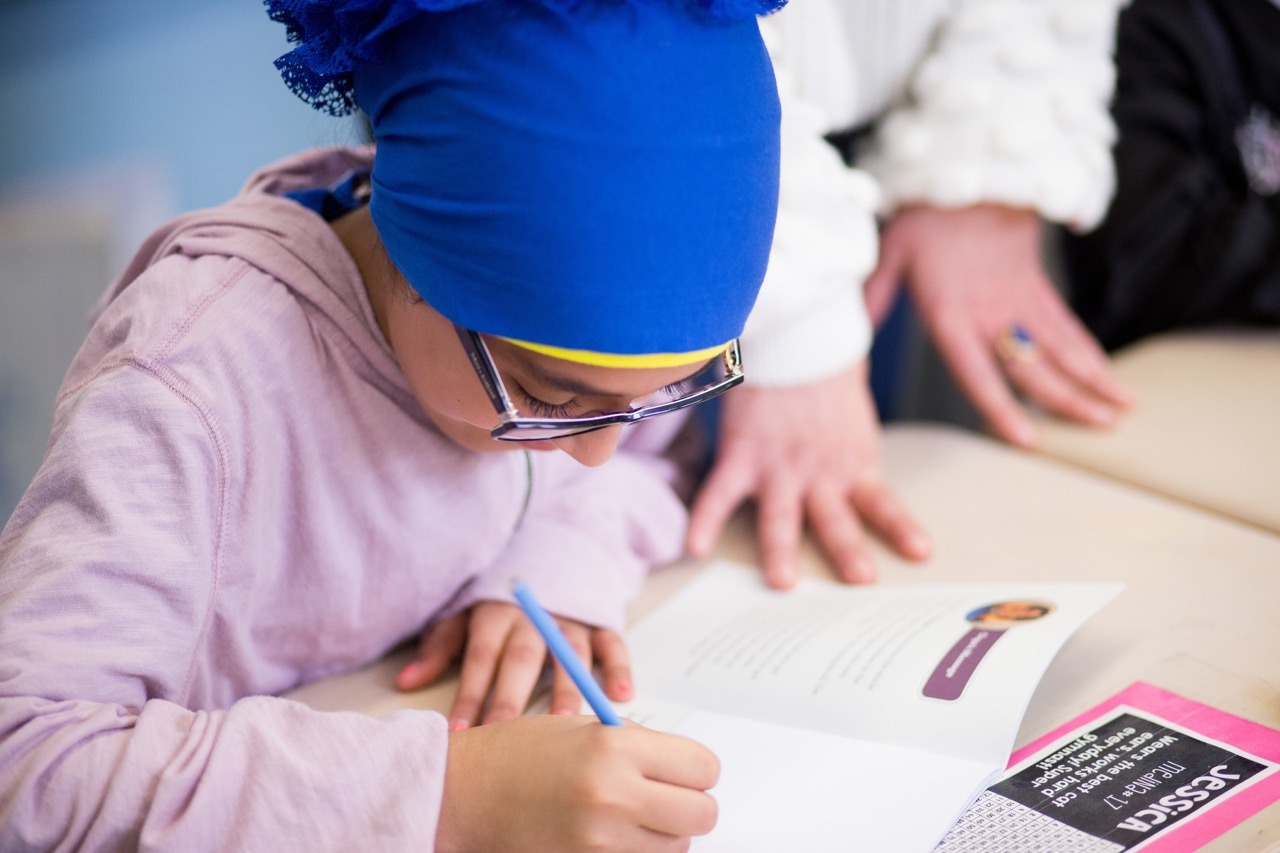 Elementray girl uses a workbook to share her thoughts.