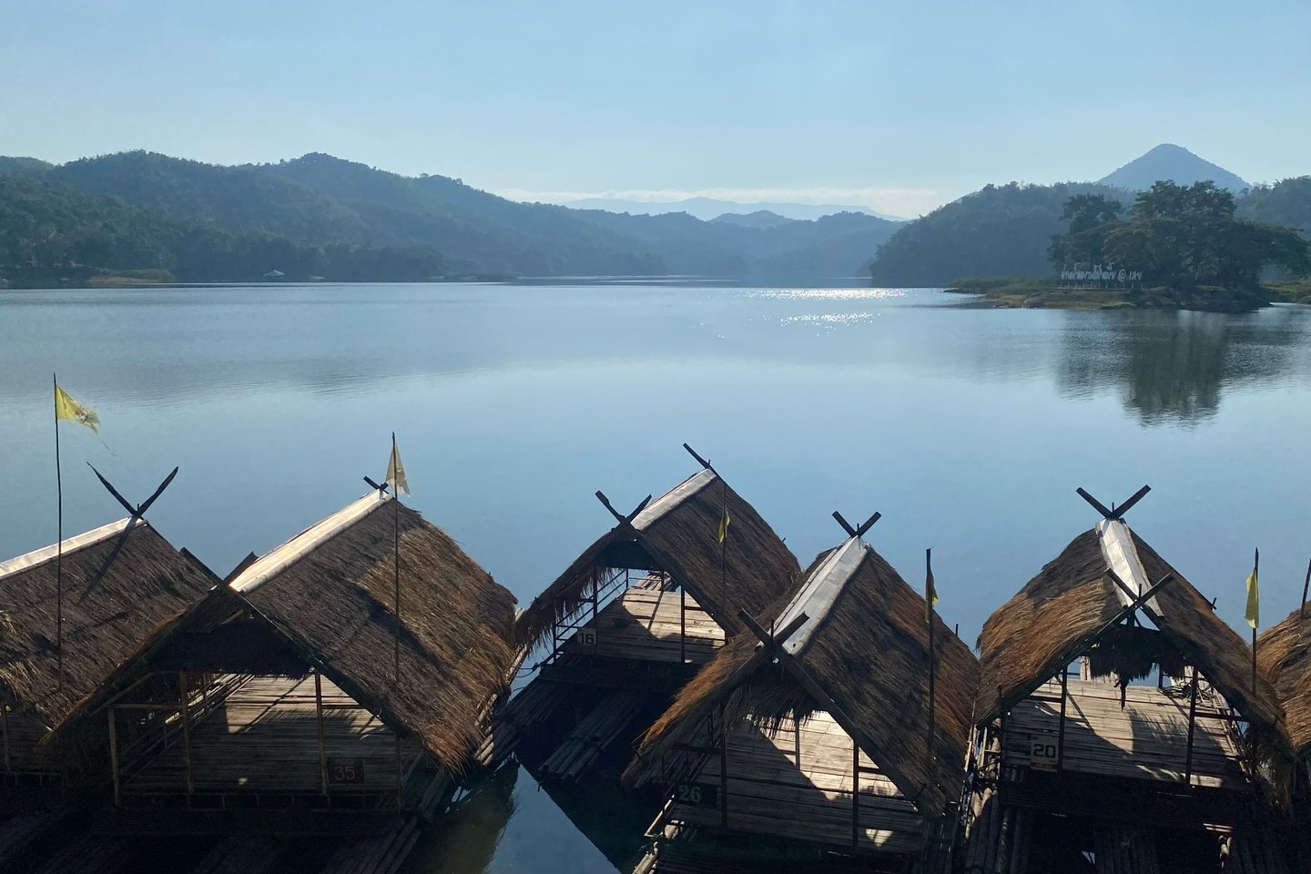 Bamboo rafts on calm water at Huai Krathing surrounded by forested hills