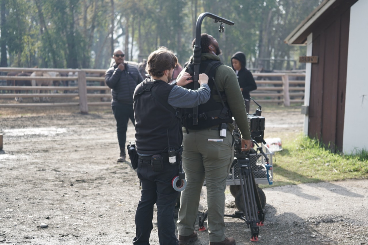 a man and woman are standing in a field working on an Easy Rig camera platform