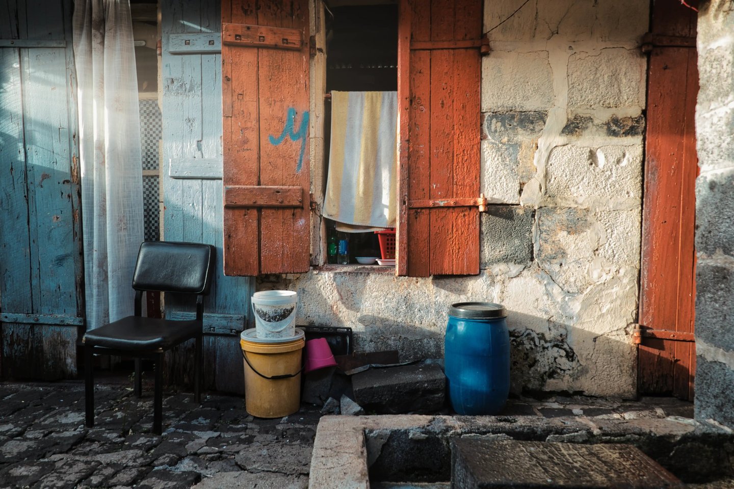 Street photography of a rustic house facade in Mauritius with colorful shutters.