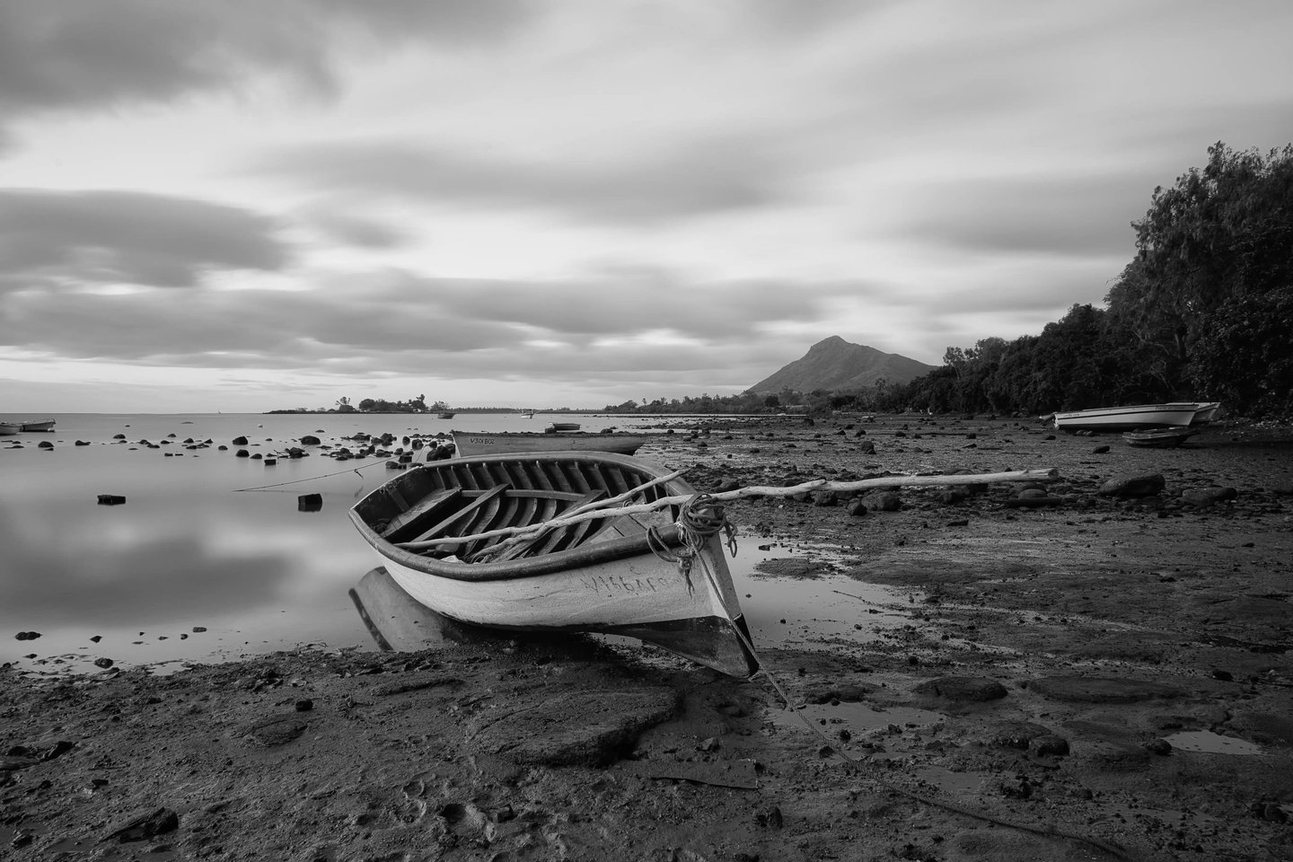 Long exposure shot of a wooden boat on a rocky shoreline at Petite Case Noyale in Mauritius