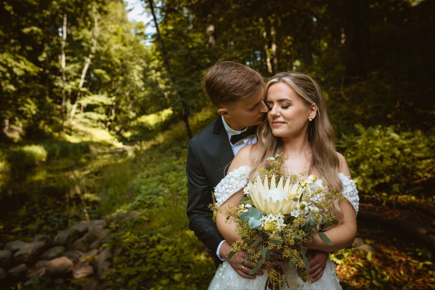 a bride and groom standing in a forest