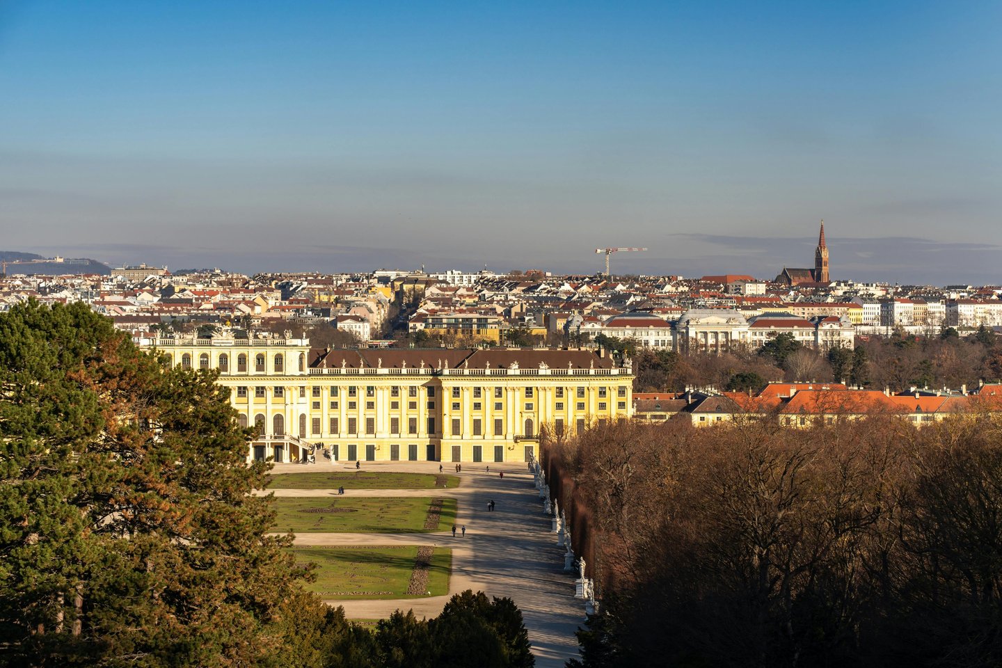Panoramic view of Schonbrunn Palace and the Vienna city skyline under a clear blue sky.