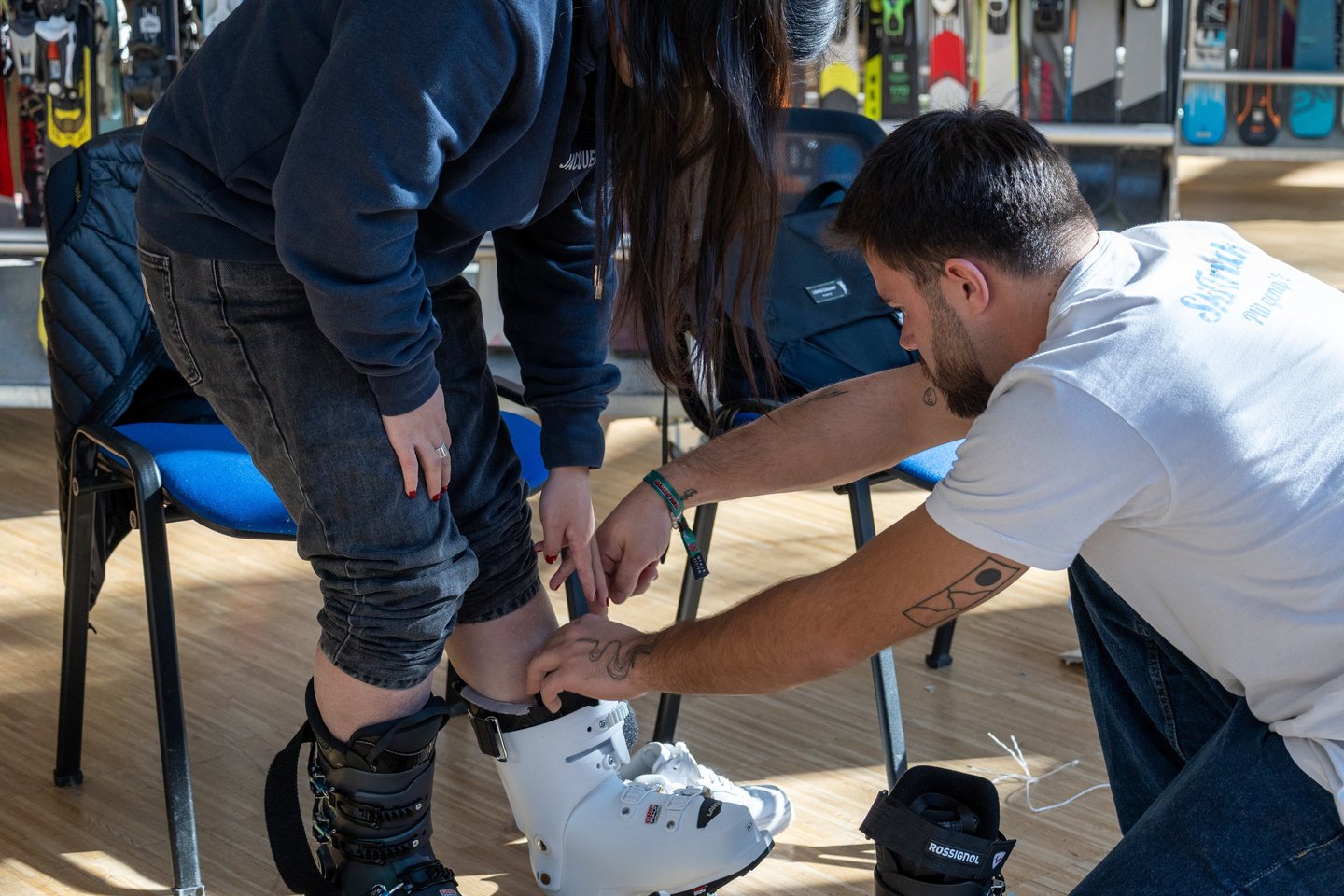 Professional ski shop technician fitting a customer with white Rossignol ski boots for a proper rental fit.