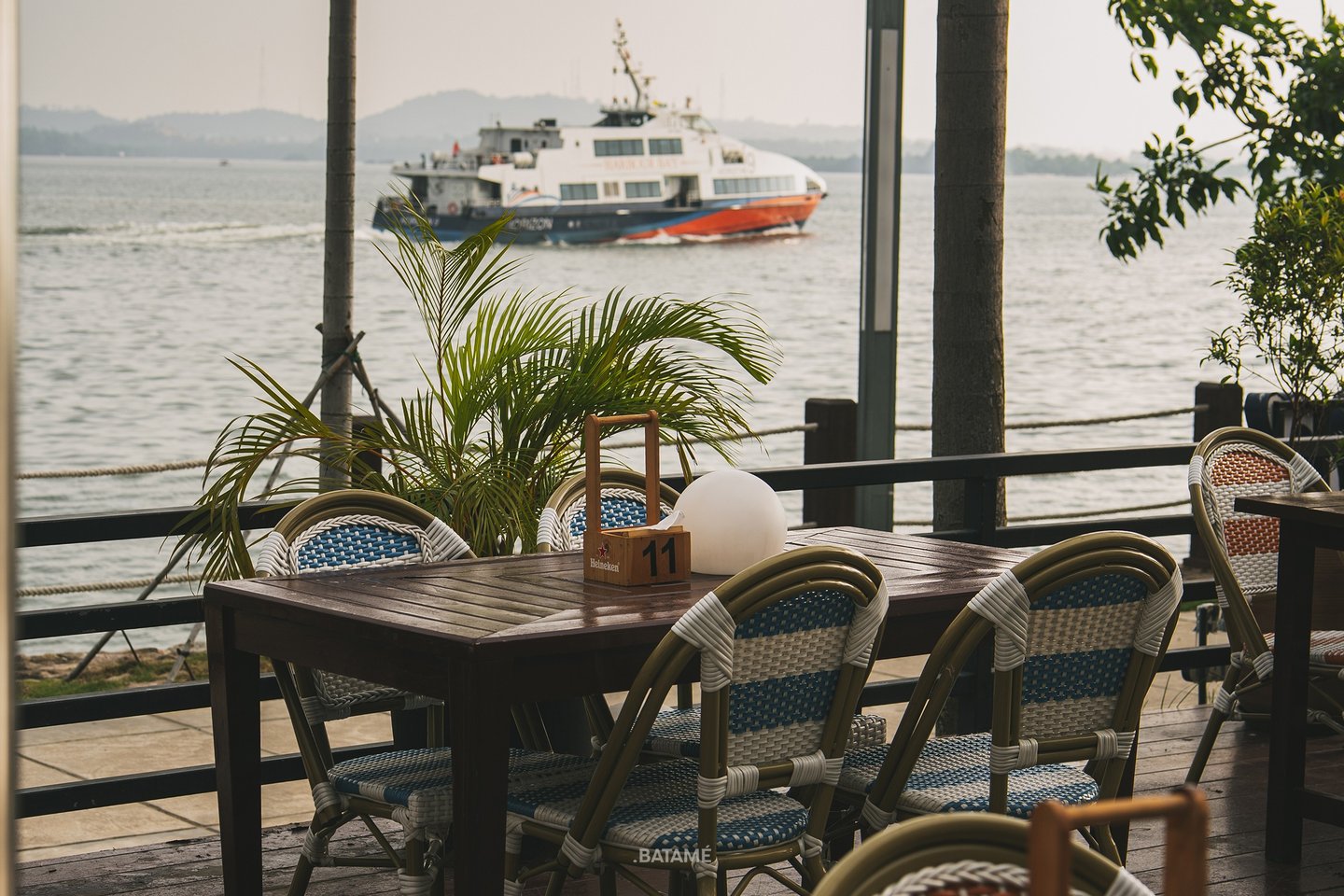 an outdoor area looking at the seaside with ferry passing by at SeeSea by Nomad Batam
