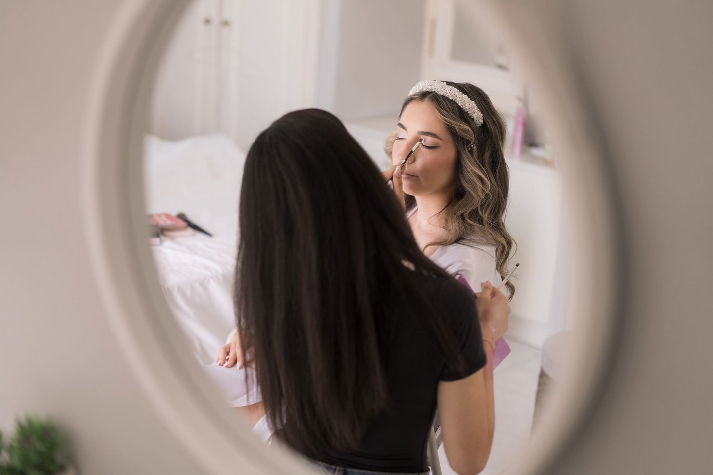 Bridal makeup artist applying soft glam foundation in natural light on wedding day