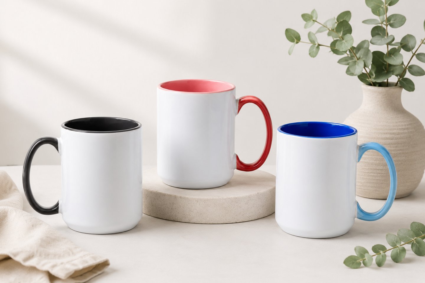 Präsentationsfoto von drei individuell personalisierbaren Keramiktassen in Grau, Rosa und Blau.