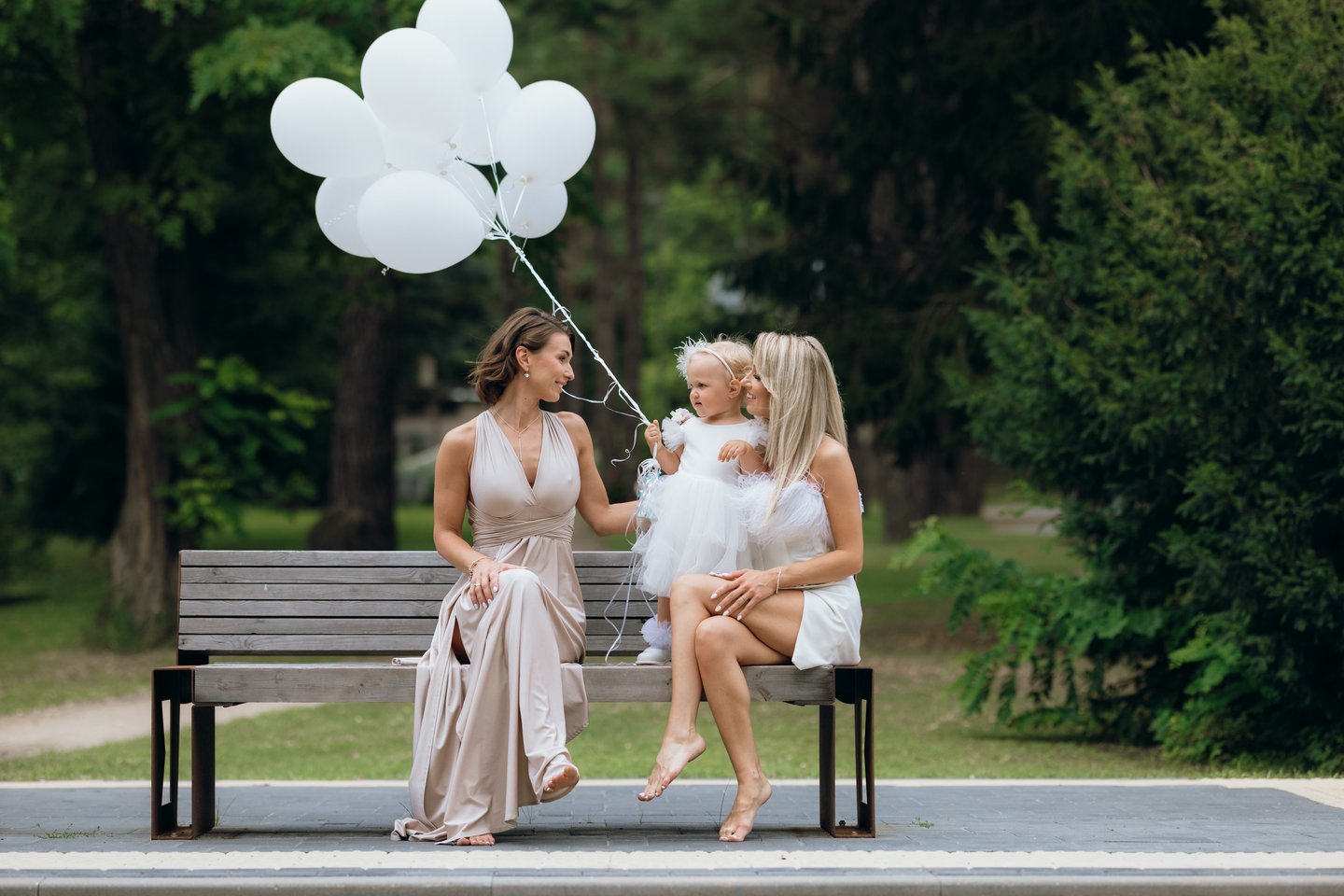 Krikštynų fotografija - krikštynų fotosesija po ceremonijos. Ant suoliuko sėdi šeima.