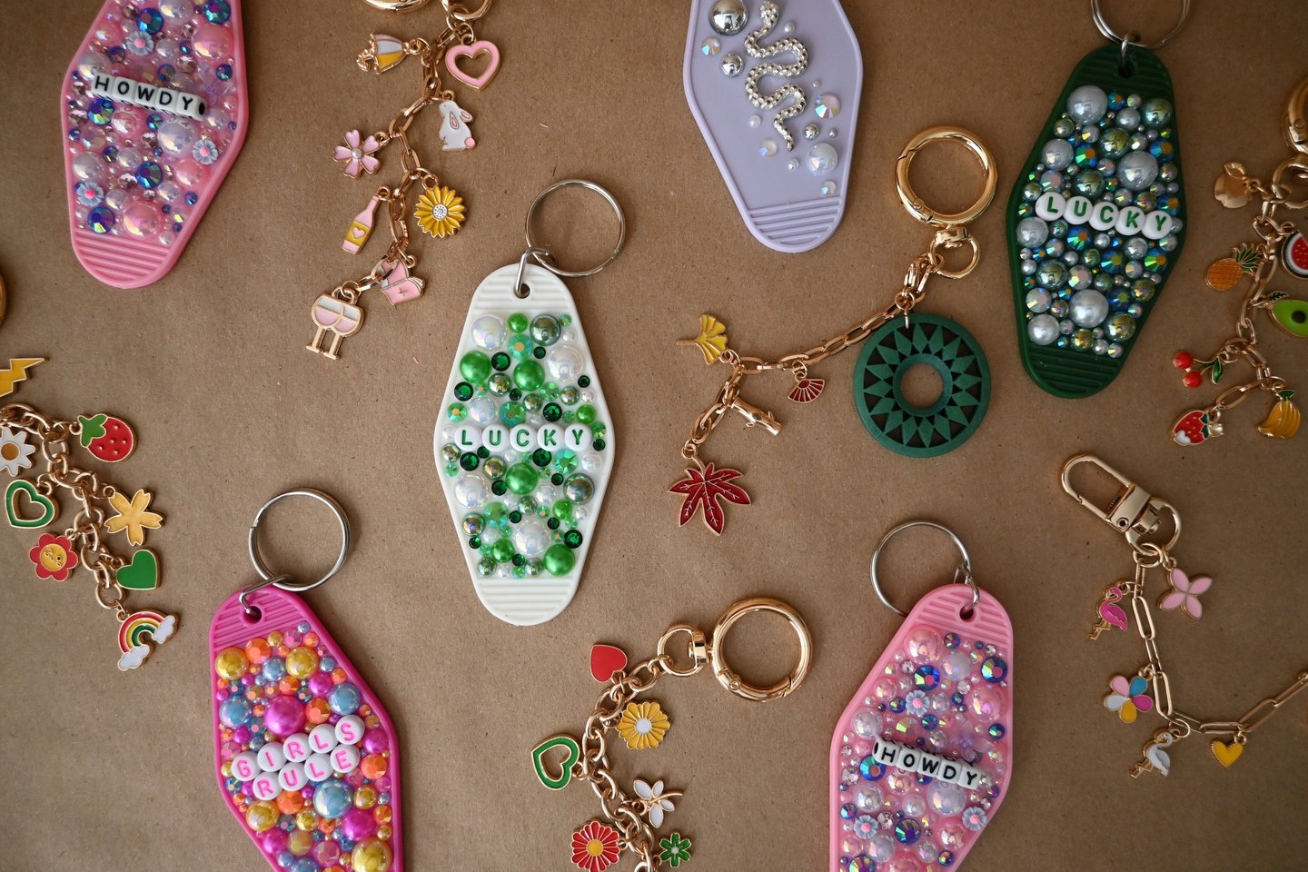 Collection of colorful beaded hotel key tag keychains with lucky and howdy charms on a brown surface.