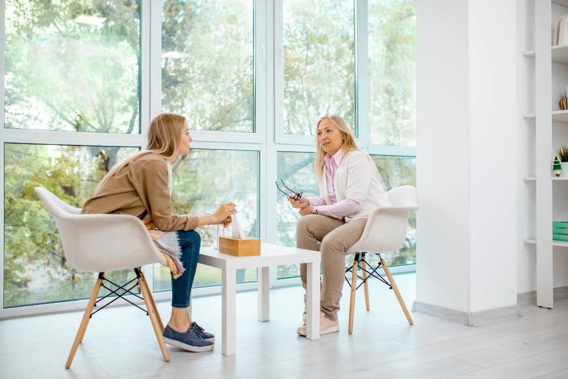 two women sitting at a table with a cup of coffee