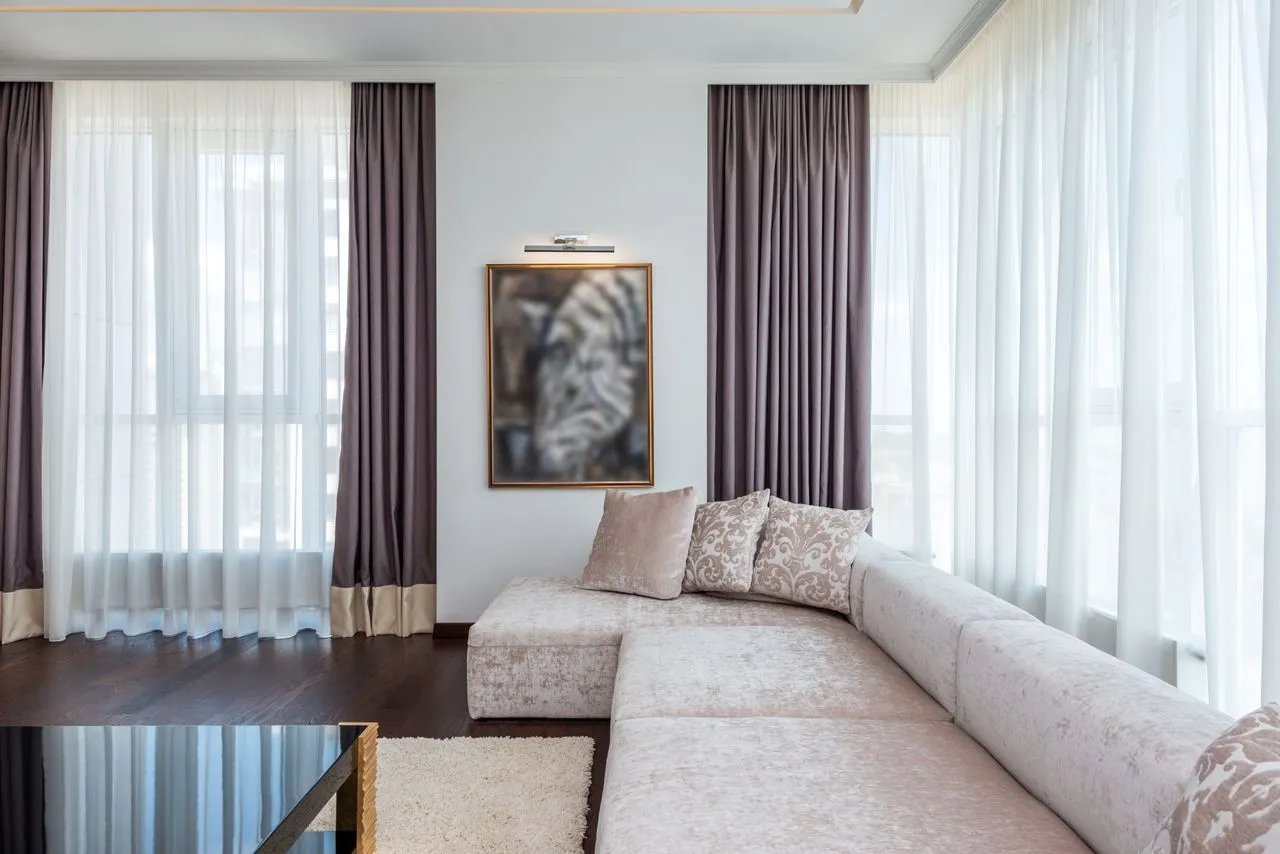 Elegant open concept living and dining room featuring white furniture, soft cream curtains, and a te