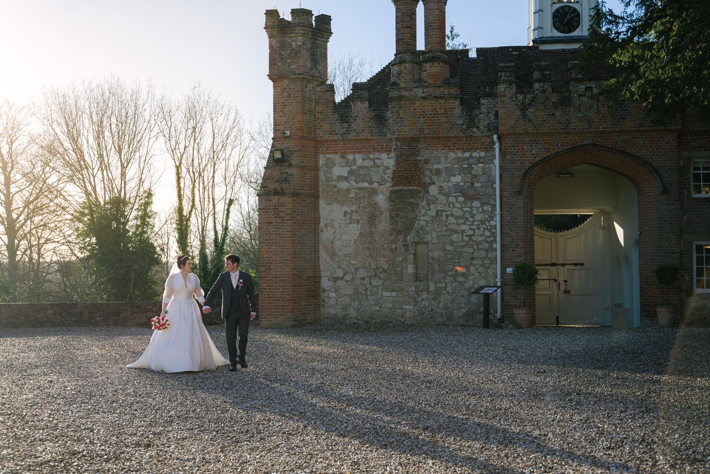 Couple walking through the courtyard at Farnham Castle during their wedding in Surrey