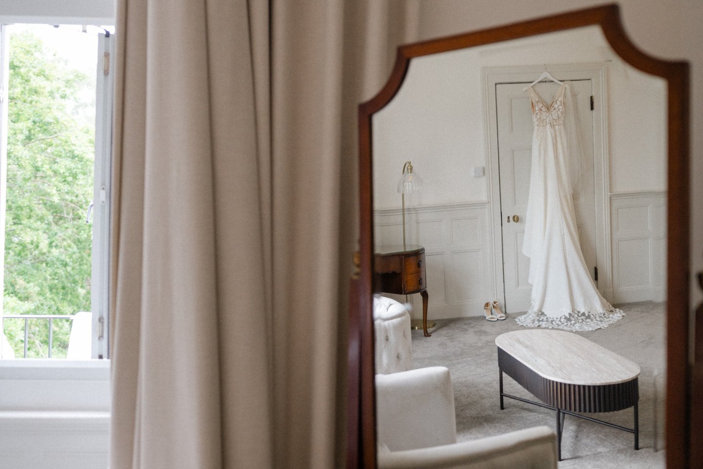 Mirror shot of wedding dress hanging from a door frame at Highley Manor