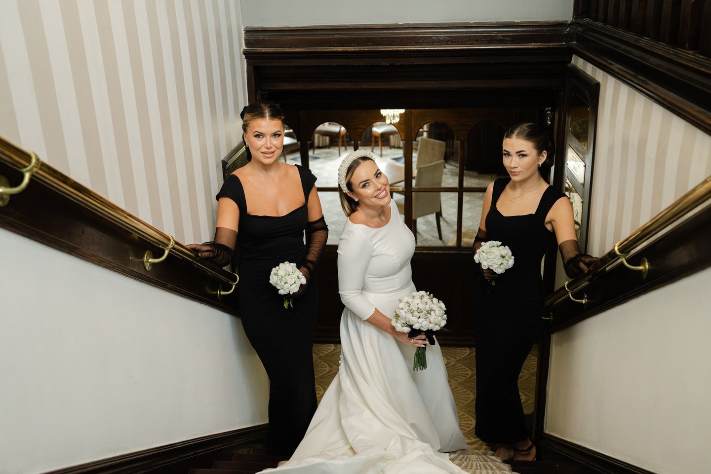 Bride and bridesmaids in a stairwell holding bouquets during wedding portraits