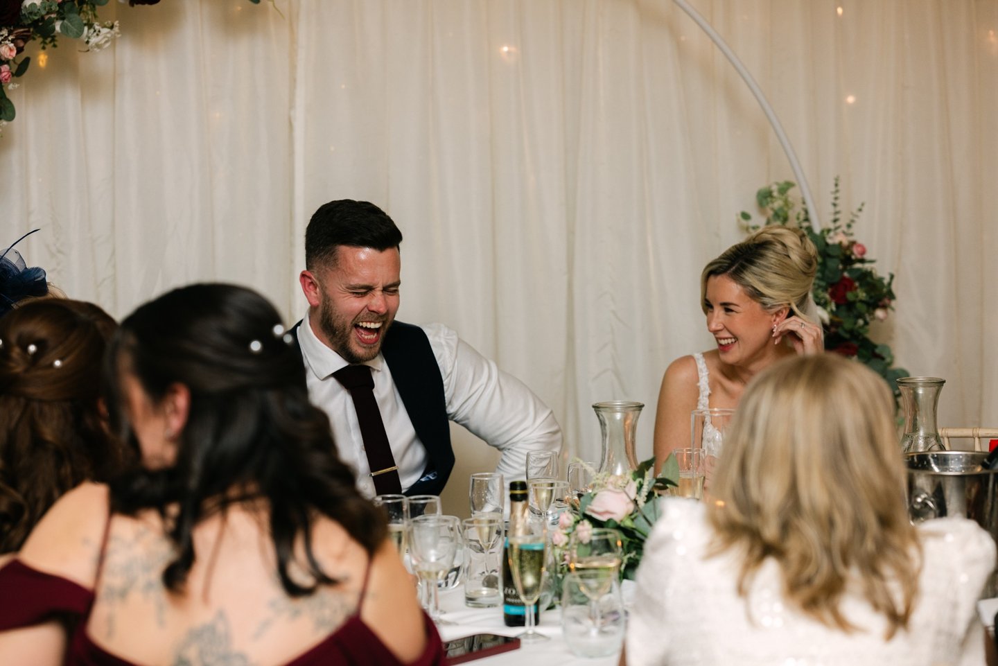 Couple laughing at the top table during their wedding reception at The Mill House Hotel