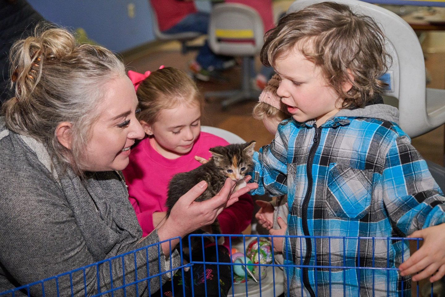 a woman holding on her hand and a boy petting it