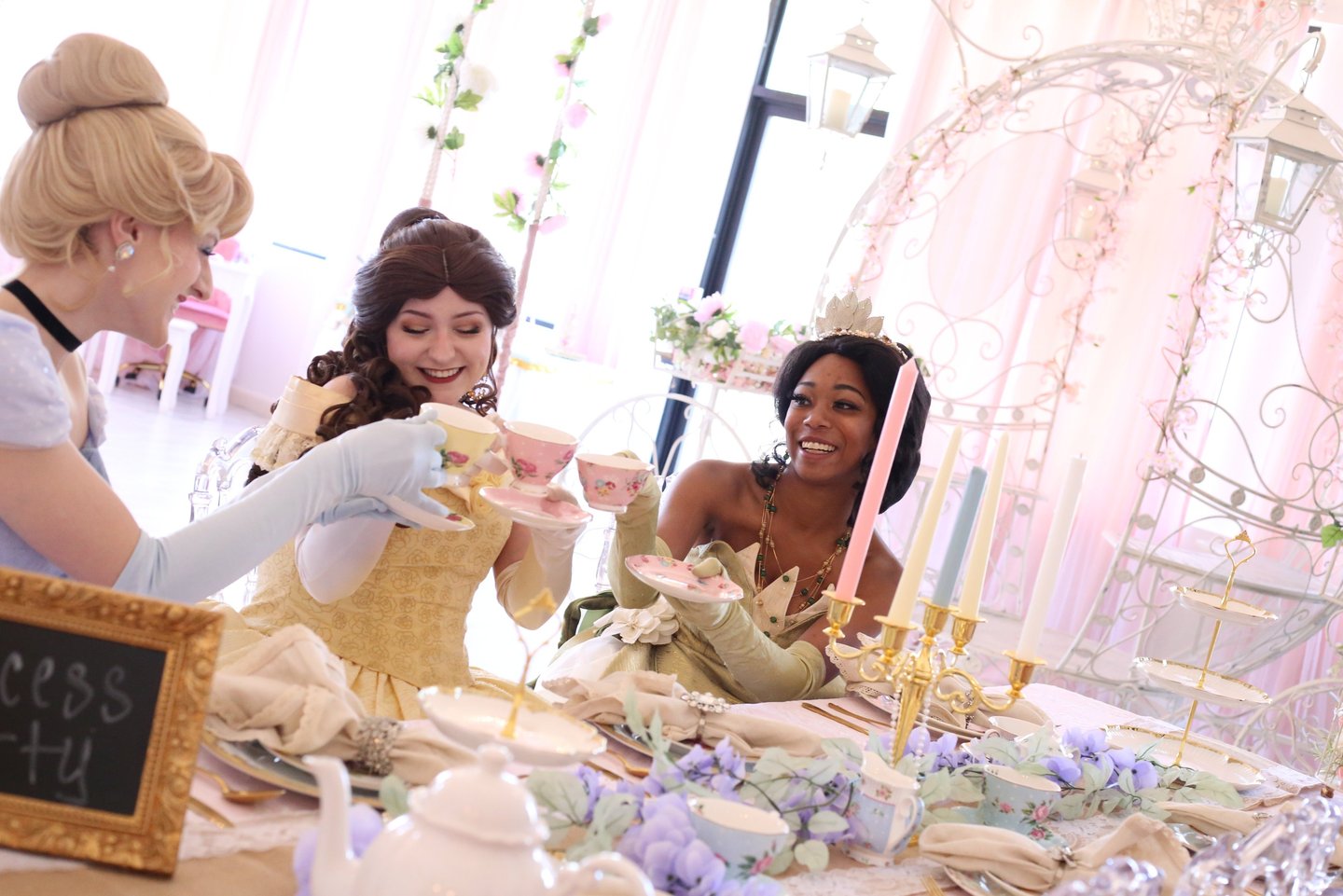 Tiana, Belle, and Cinderella cheers with tea cups