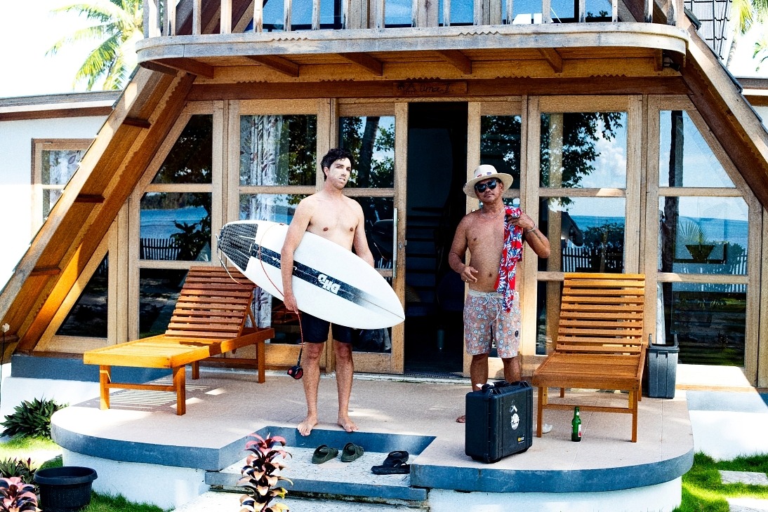 a man standing on a porch with a surfboard
