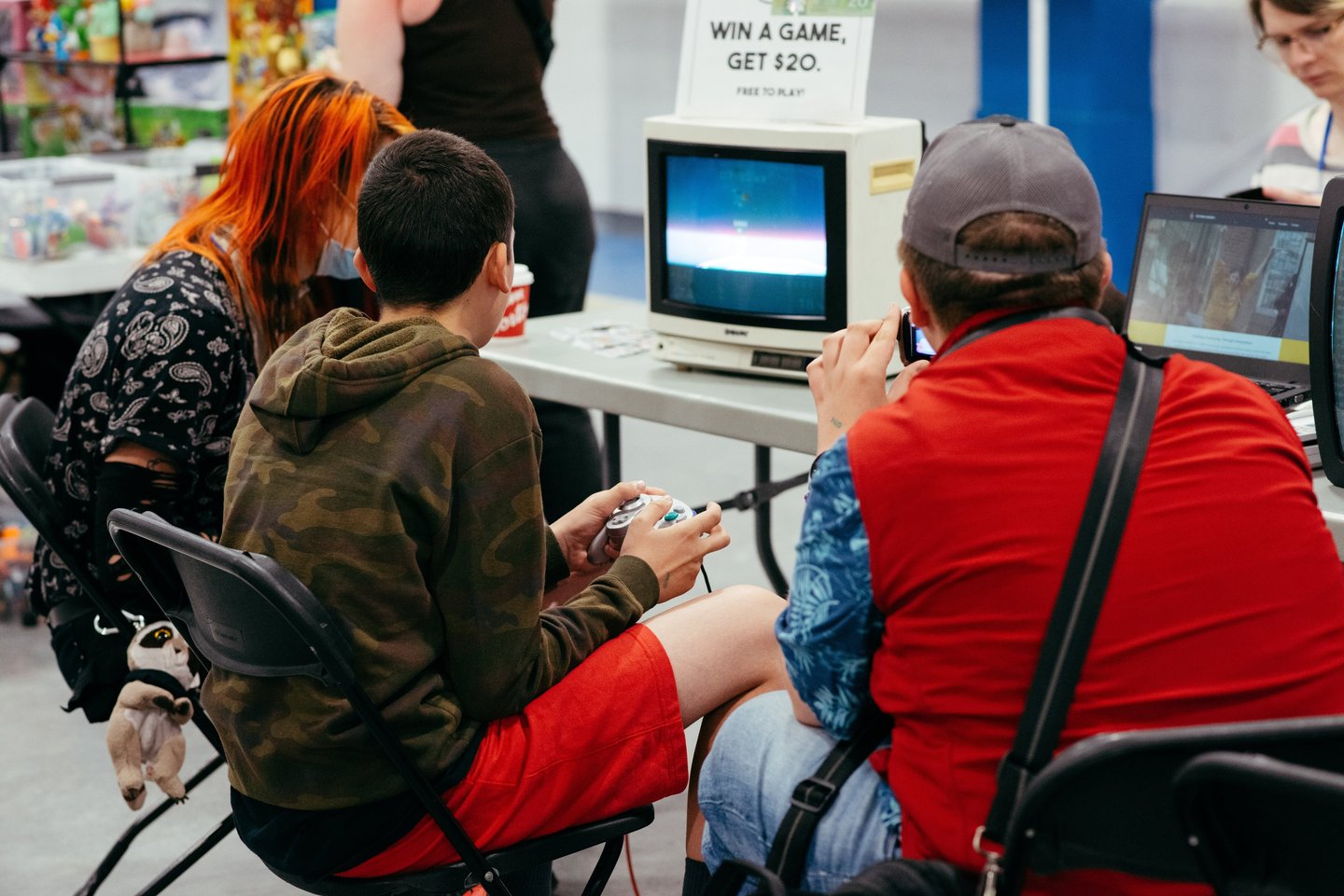 Close up image of two people sitting at an old tv playing some video games together at the event.
