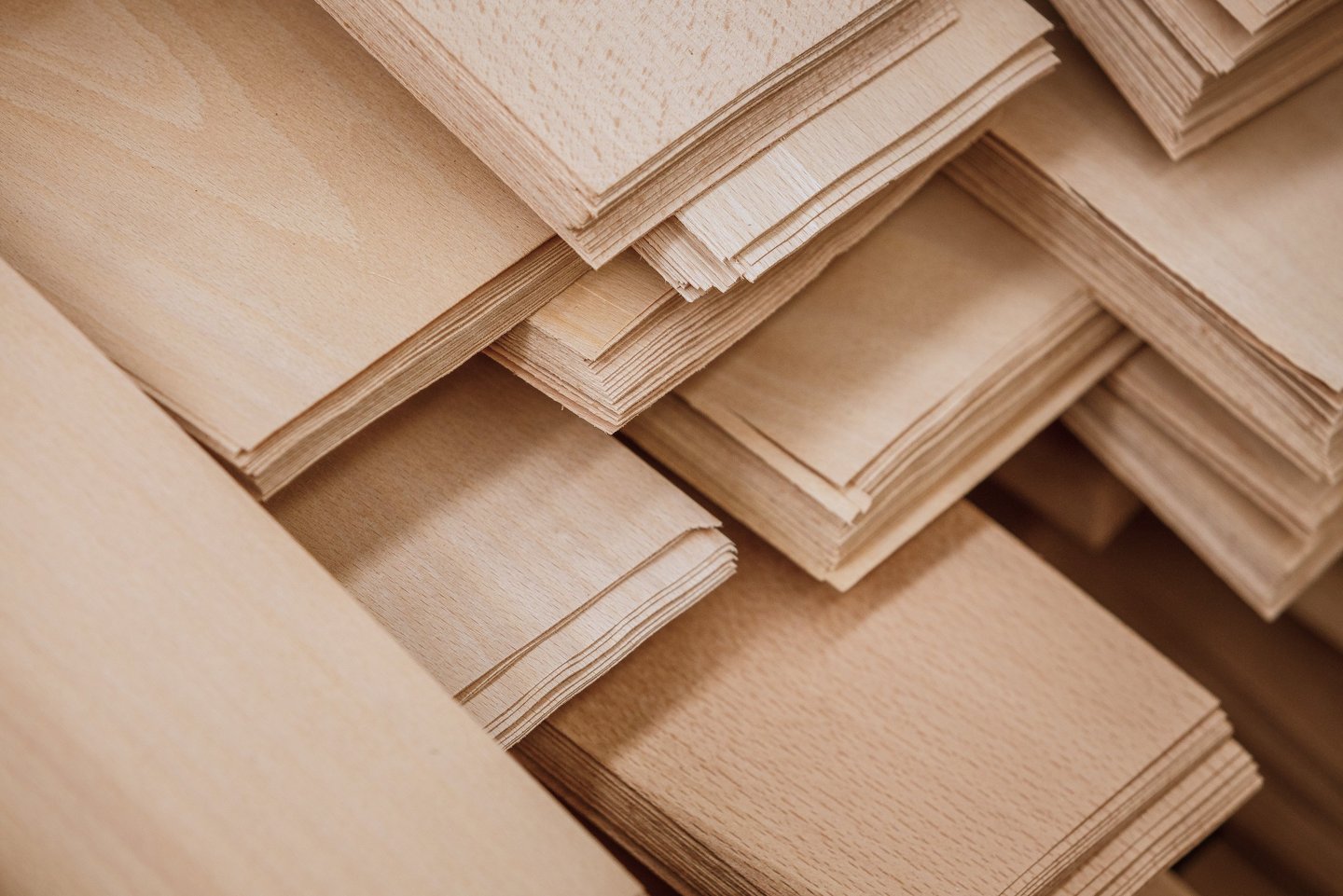 Stacks of high-quality light wood veneer sheets for carpentry and furniture manufacturing.