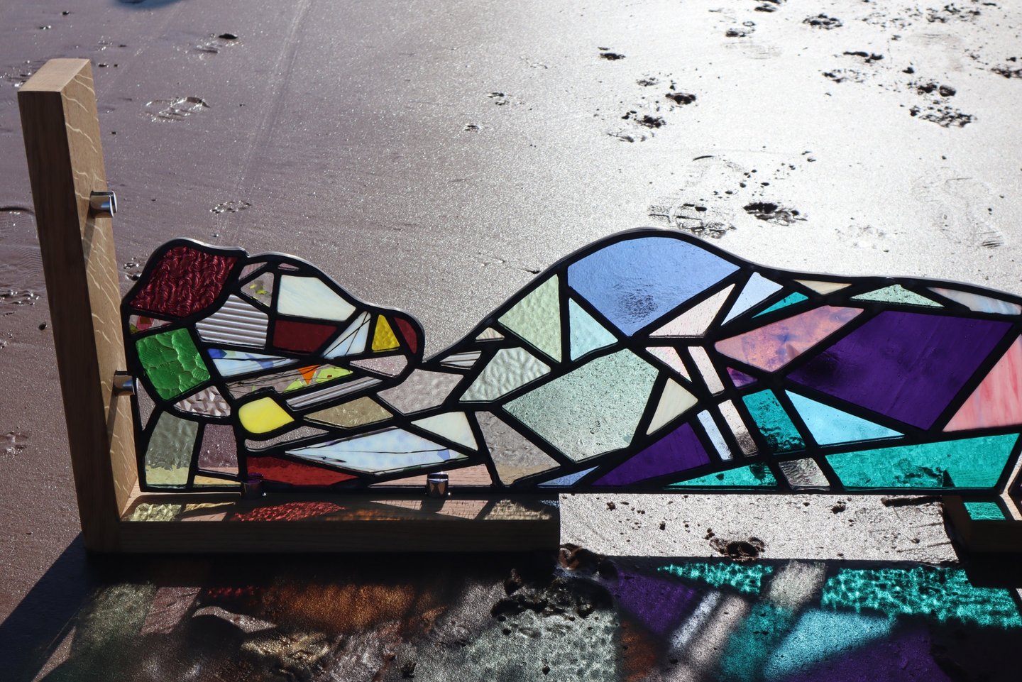 Full Sized Stained Glass Woman. Photograph is taken on a beach at low tide. Art work by Laura Kriefman