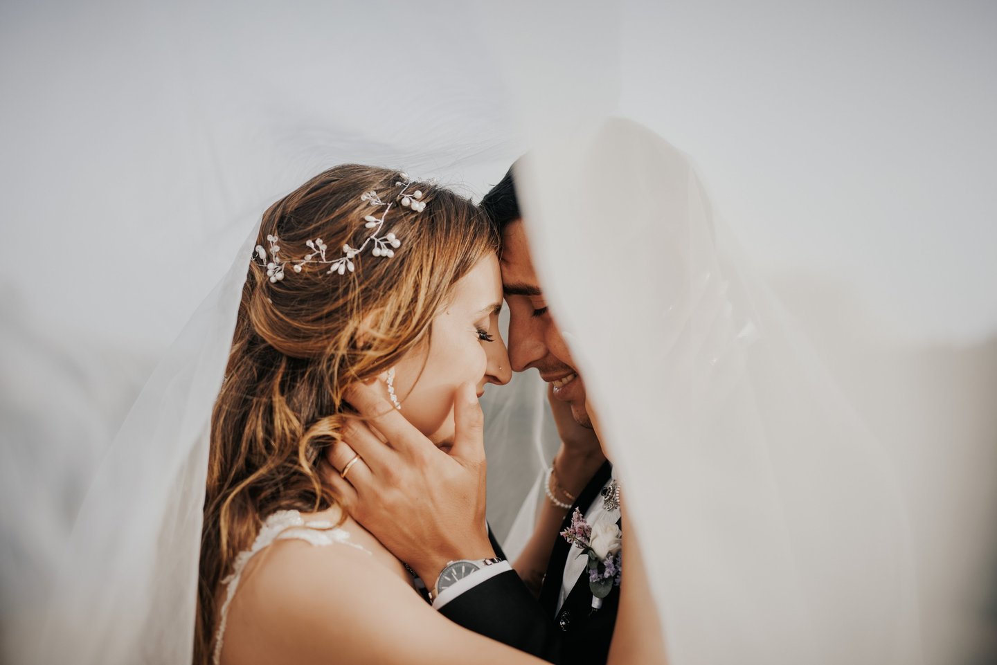 sposo e sposa abbracciati sotto al velo