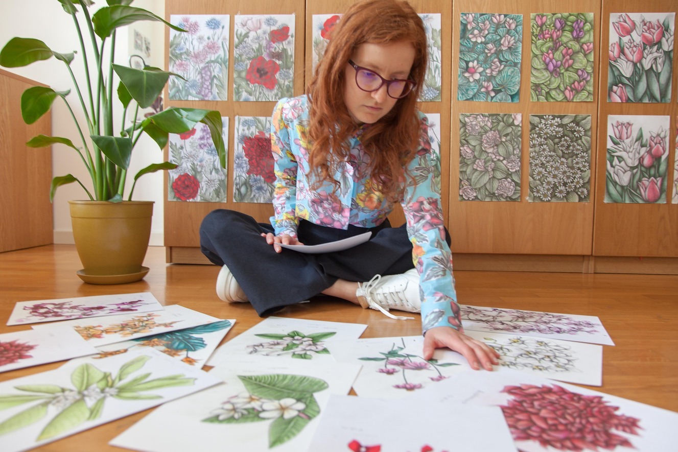 A Woman sat on the floor surrounded by botanical illustrations
