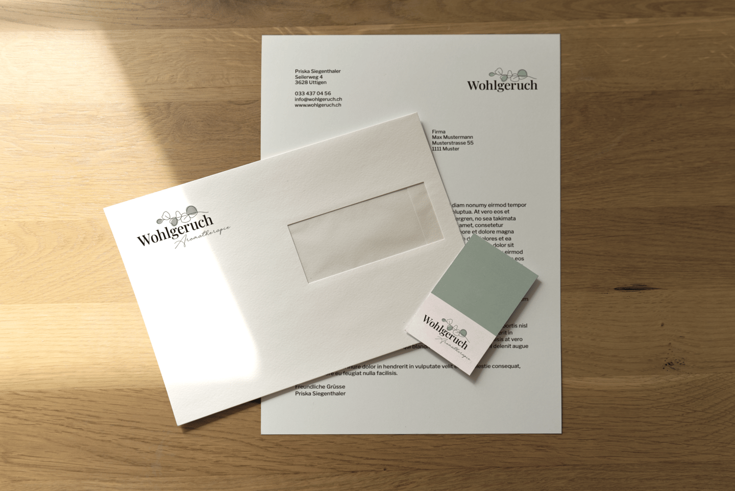 Briefschaft mit dem Logo von Wohlgeruch Aromatherapie auf einem Holztisch im Sonnenlicht.