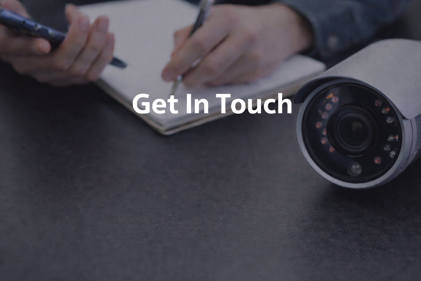 Security camera on desk beside notepad and phone during consultation planning