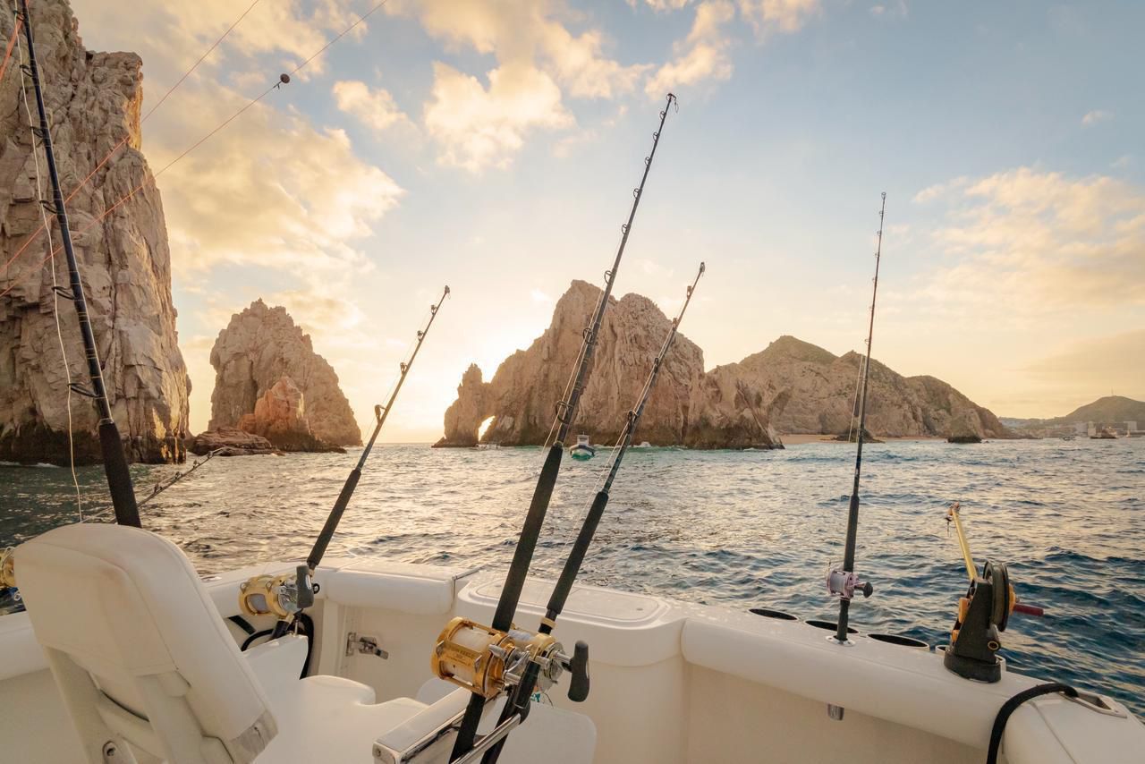 Deep sea fishing boat at sunset near El Arco rock formations in Cabo San Lucas.