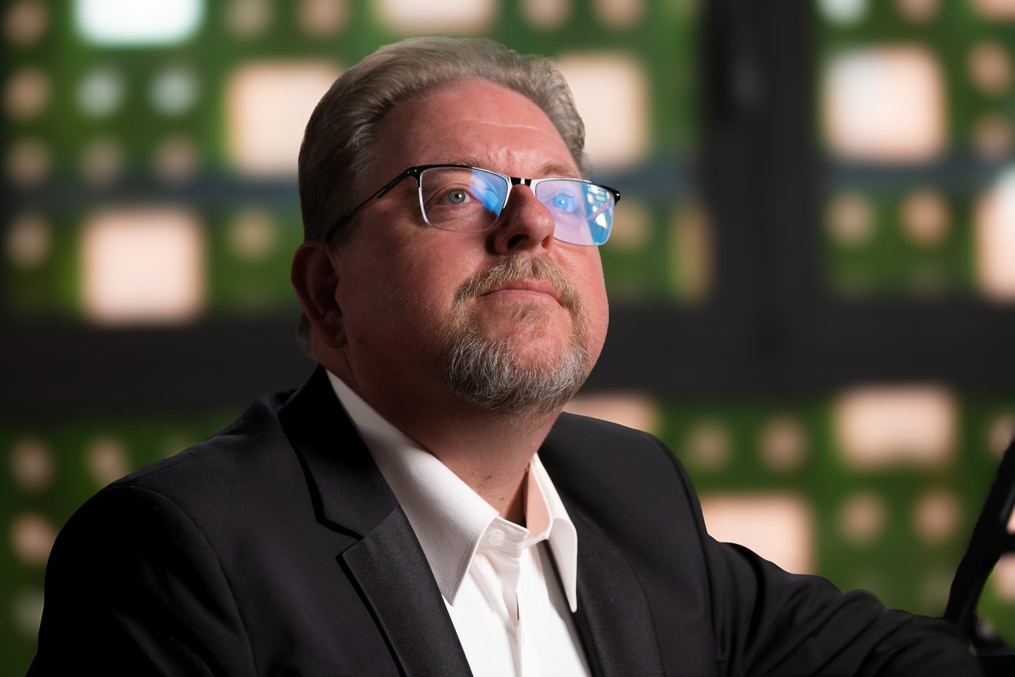 Robert in a suit and glasses holding a cell phone