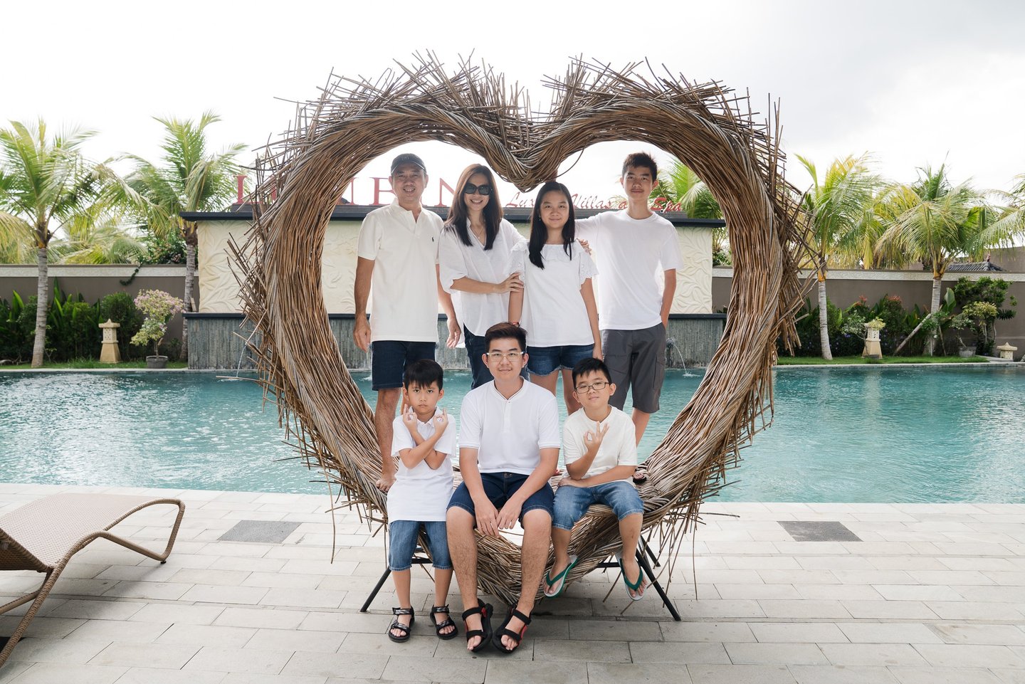 Family portrait inside heart frame during extended family photography at Lumbini Villas Jimbaran Bali by the pool
