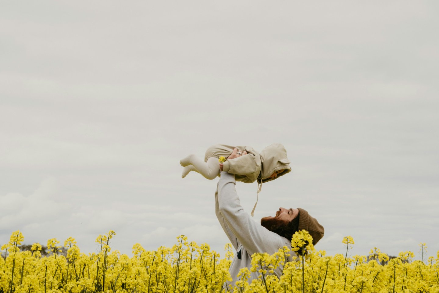 a man holding a baby in a field