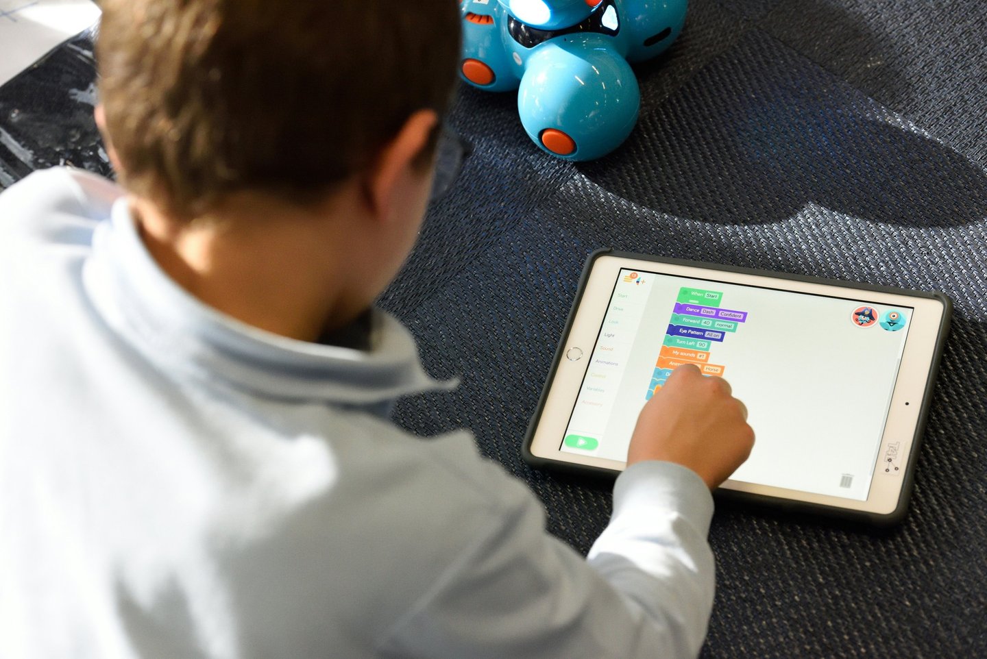 a boy playing with a tablet computer and a robot