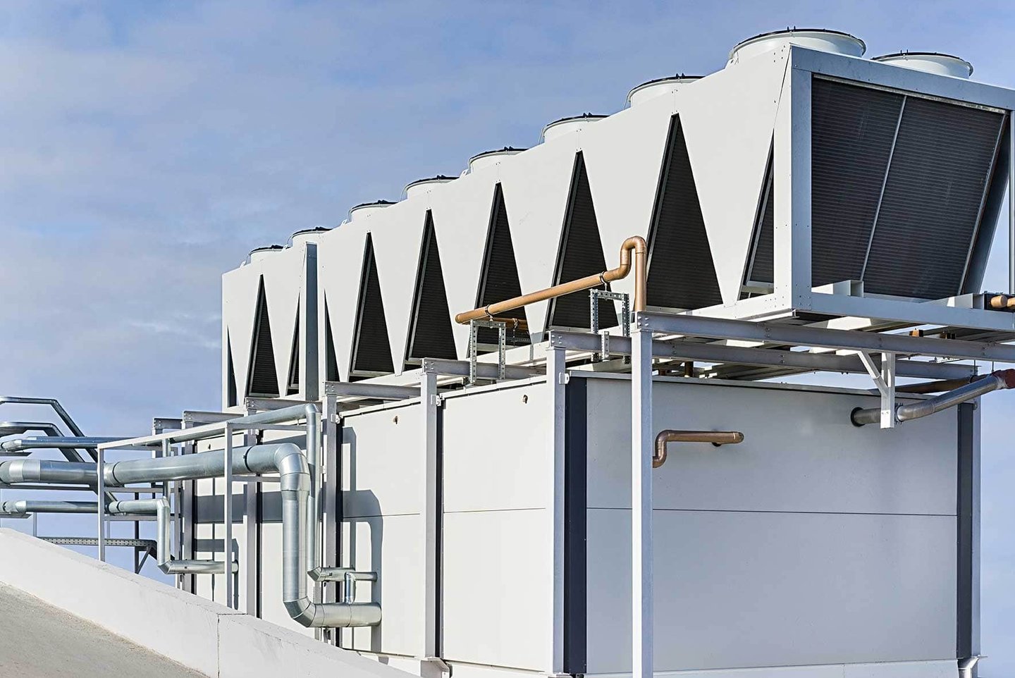 Industrial rooftop HVAC system with air-cooled condensers and water piping.