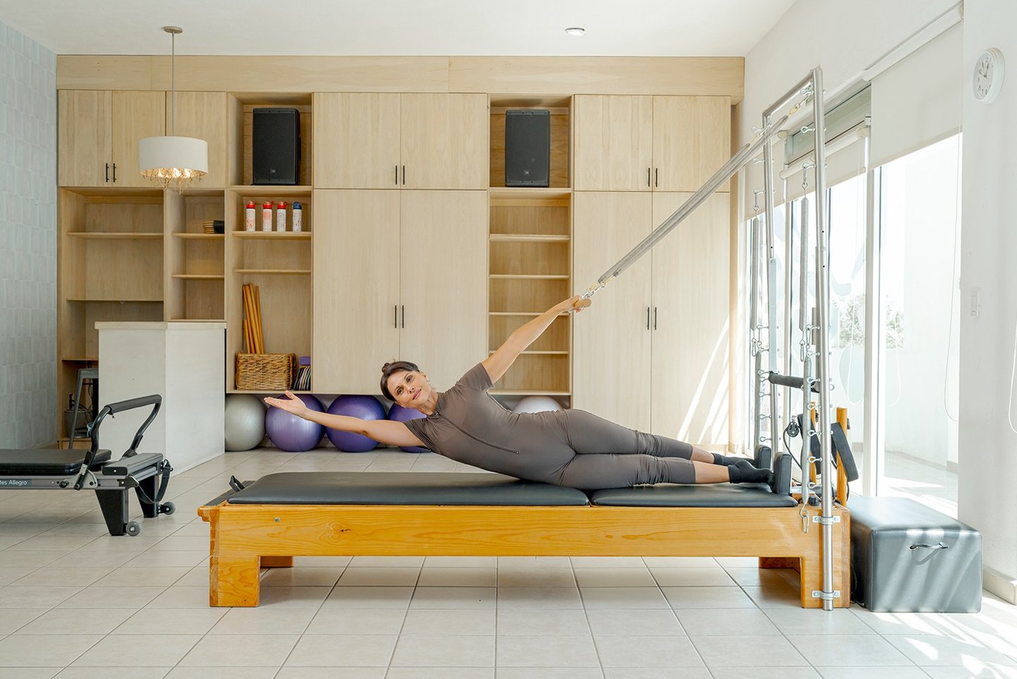 Woman performing a side-lying torso stretch using the springs of a Cadillac Pilates unit.