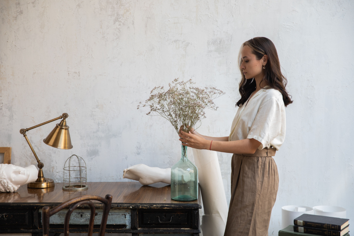 a woman putting dried foliage into a vase