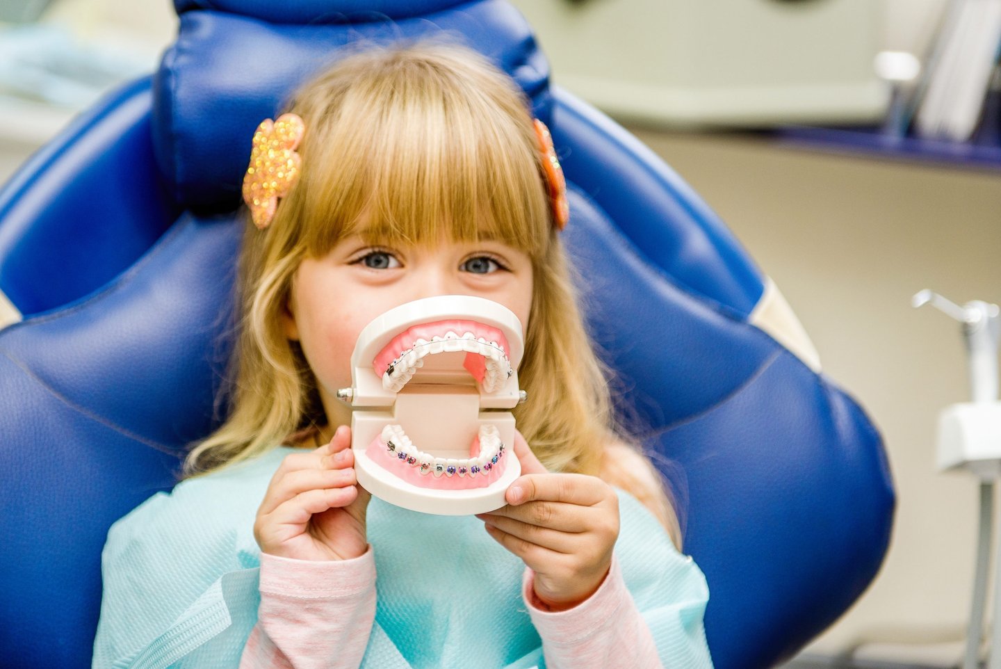 a little girl sitting in a chair with a toothbrush