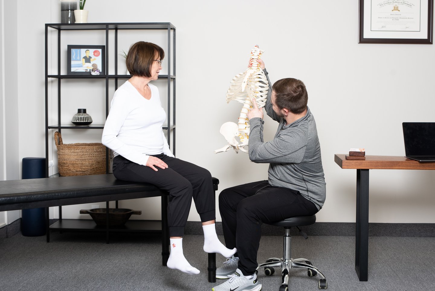 Osteopathic practitioner educating the patient on the spine  