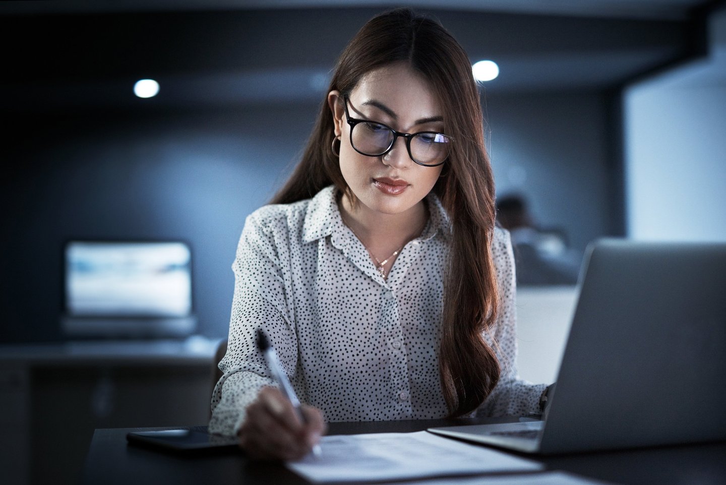 Professional woman with glasses working late on a laptop